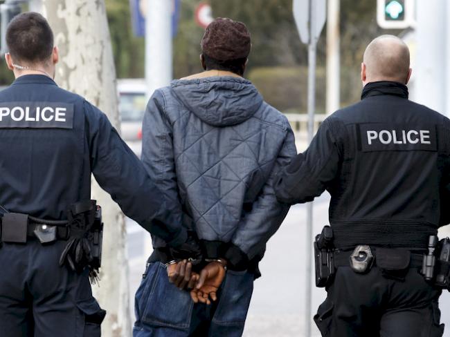 Genfer Polizisten führen einen Mann in Handschellen ab (Symbolbild)
