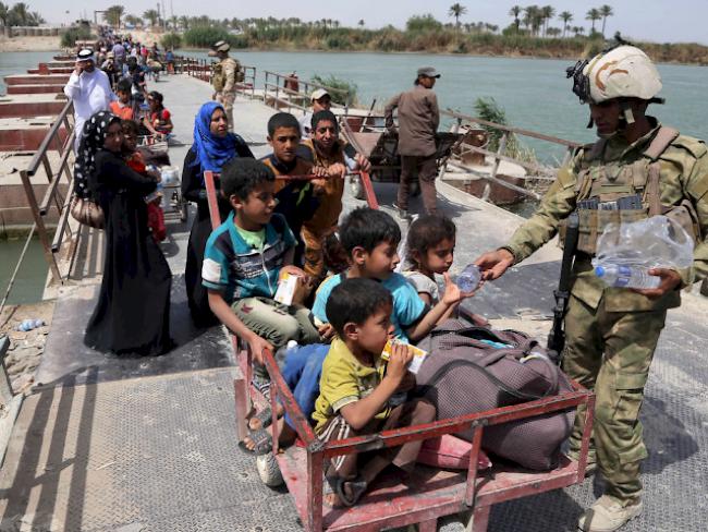 Iraq security troops distribute bottles of water to displaced families from Ramadi on Bzebiz bridge 65 km west of Baghdad., Iraq, Saturday, April 18, 2015. Thousands of displaced people form Ramadi city continue to pour to Baghdad, fleeing the ongoing fighting in Anbar provincial capital between Iraqi security forces and fighters from Islamic State militant group.  (AP Photo/Karim Kadim)