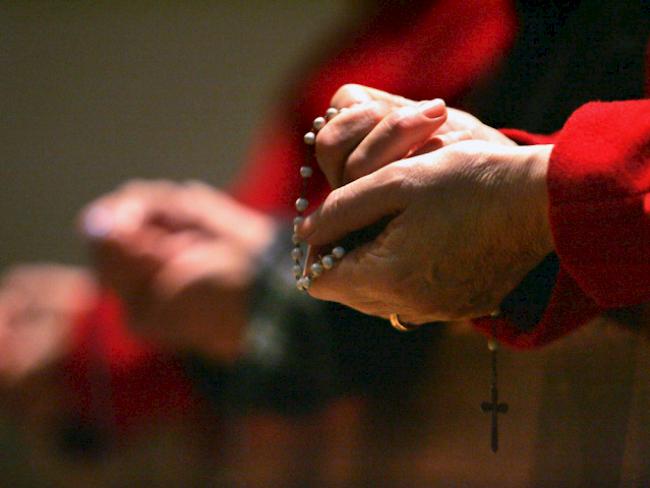 Eine Gläubige betet in einer Kirche den Rosenkranz (Archiv)