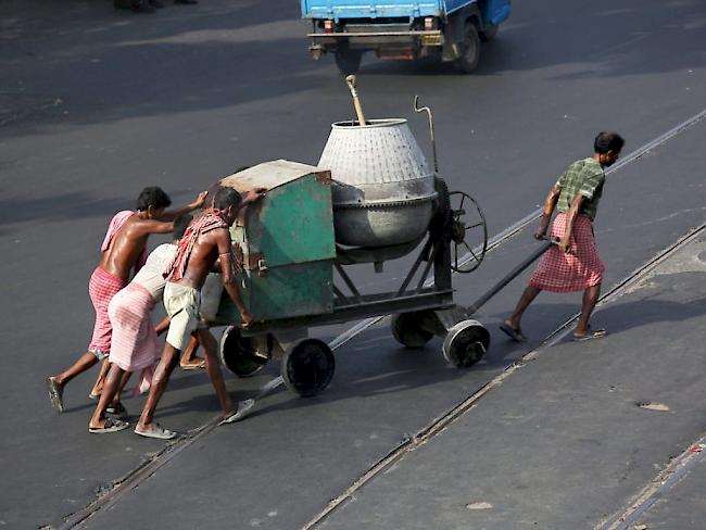 Indische Arbeiter am Donnerstag in Kalkutta beim Schieben eines Betonmixers in brütender Hitze