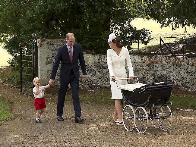 Prinz George an der Hand seines Vaters William und Mutter Kate mit dem Kinderwagen, in welchem Prinzessin Charlotte zur Taufe gefahren wird.