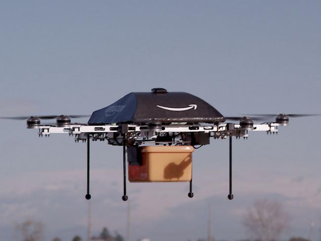 An eine Mini-Drohne des Online-Händlers Amazon ist eine Paketkiste befestigt. In 30 Minuten soll die Fracht beim Kunden eintreffen. (Archiv)