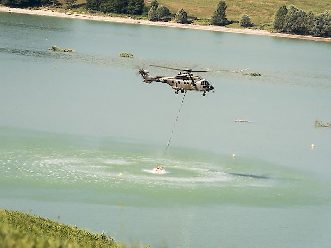 Ein Armeehelikopter entnimmt Wasser aus dem Greyerzersee, um damit Kühe in den Freiburger Voralpen zu tränken. (Archiv)