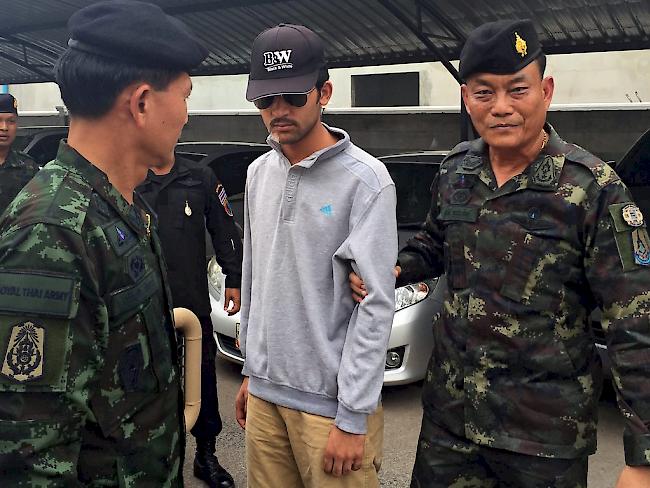 Der mutmassliche Bombenleger wird von thailändischen Sicherheitskräften abgeführt. Er soll aus der Unruheregion Xinjiang in Nordwestchina stammen