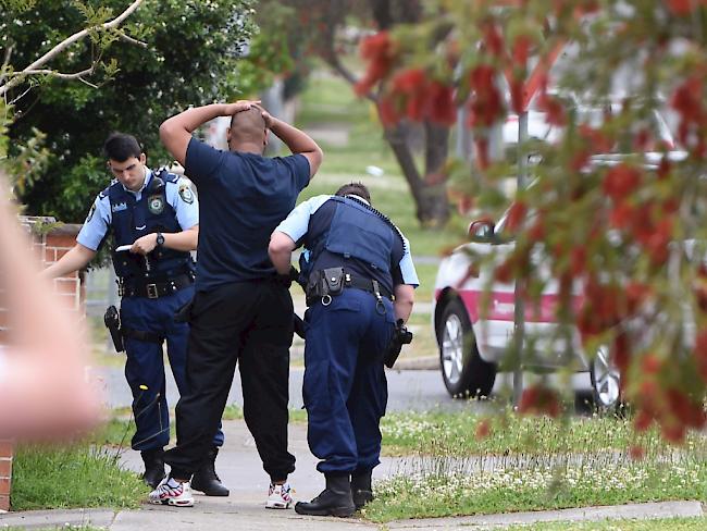 Polizisten im Westen der australischen Metropole Sydney kontrollieren einen Mann im Rahmen mehrerer Festnahmen nach dem Terroranschlag.