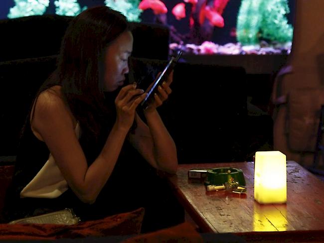 Eine Chinesin hält in einer Pekinger Bar eine Zigarette in der Hand und schaut auf ihr Smartphone. Gemäss der Studie in "The Lancet" waren unter den Raucher-Toten im Jahr 2010 neben 840