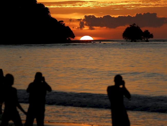 Touristen fotografieren auf Phuket den Sonnenuntergang. Die thailändische Insel, welche nun auch von den Rauchschwaden infolge illegaler Brandrodung in Indonesien betroffen ist, gehört zu den wichtigsten Touristendestinationen Südostasiens (Archiv)