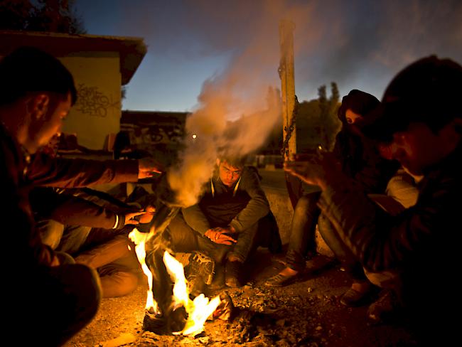 Afghanische Flüchtlinge wärmen sich auf Lesbos an einem Feuer. Auf der griechischen Insel soll in den kommenden Tagen der erste Hotspot für die Registrierung von Flüchtlingen seinen Betrieb aufnehmen (Archiv)