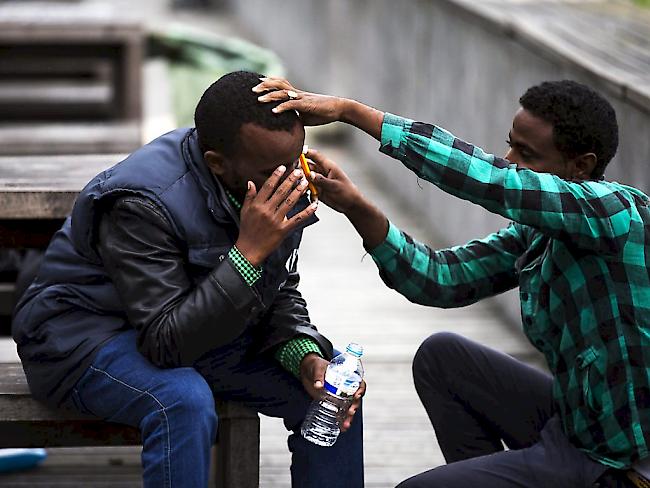 Ein Flüchtling aus Eritrea hilft seinem Freund in einem Park in Paris. Laut  Amnesty International ist die  ausufernde Wehrpflicht in Eritrea ein häufiger Fluchtgrund. Wehrpflichtige würden oft jahrzehntelang als Zwangsarbeiter in der Landwirtschaft oder am Bau eingesetzt.(Archivbild)