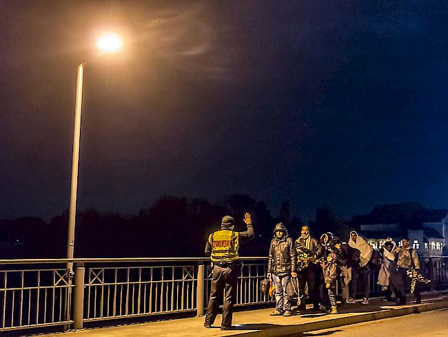 Ein Grenzpolizist stoppt Flüchtlinge auf einer Brücke zwischen Österreich und Deutschland.