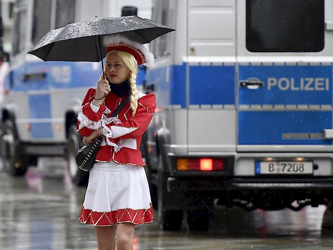 Eine kostümierte Frau mit Schirm vor einem Polizeiauto in Köln. Anders als in Düsseldorf und Mainz wird in der bevölkerungsreichsten Stadt des Bundeslandes Nordrhein-Westfalen der Rosenmontagszug durchgeführt - wenn auch mit einigen Einschränkungen (Archiv)