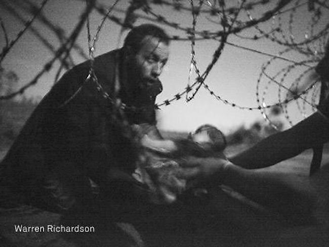 Das Sieger-Foto der World Press Photo 16 von Warren Richardson zeigt einen Flüchtling, der ein Baby unter einem Zaun hindurchreicht. Dieses und weitere prämierte Bilder sind derzeit in Zürich zu sehen.