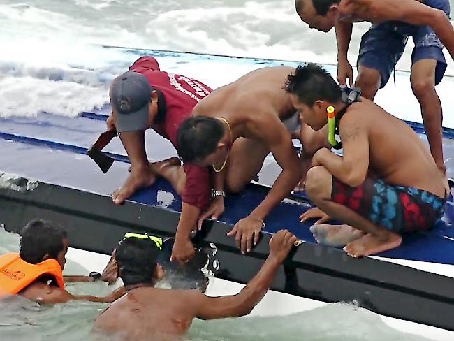 Helfer versuchen Touristen aus einem gekenterten Boot zu bergen. Bei dem Unglück starben mindestens drei Menschen.