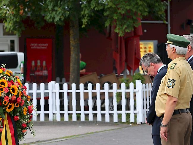 Deutschlands Innenminister Thomas de Maizière (links) gedenkt der Opfer des Amoklaufs.