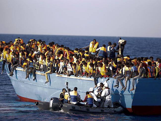 Italienische Rettungskräfte bergen eine Frau von einem überladenen Flüchtlingsschiff vor der Küste Libyens.