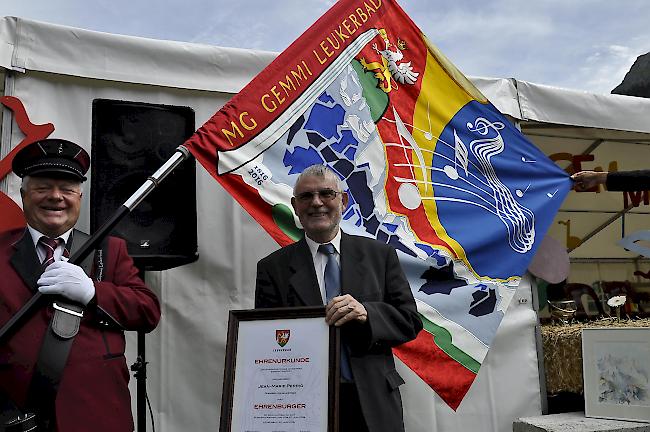 Pfarrer Perrig mit der Urkunde und der Fahne im Hintergrund.