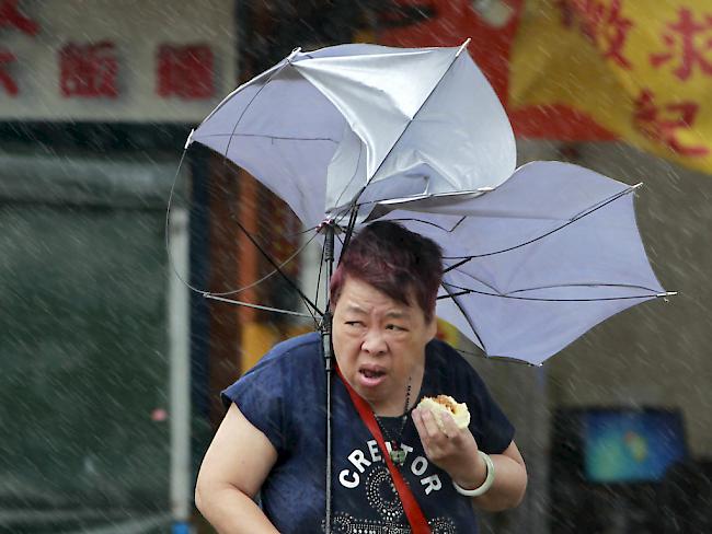 Frau mit vom Sturm "Megi" ramponiertem Regenschirm am Dienstag in Taiwan.