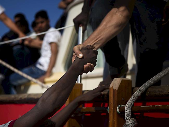 Ein Helfer hilft einem Flüchtling von einem überladenen Boot auf ein Rettungsschiff. (Archiv)