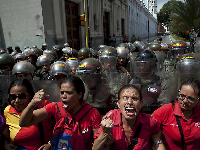 Anhänger des  venezolanischen Präsidenten Nicolas Maduro protestieren vor dem schwer bewachten Parlament. Das Parlament hat ein politisches Verfahren gegen Maduro eröffnet.