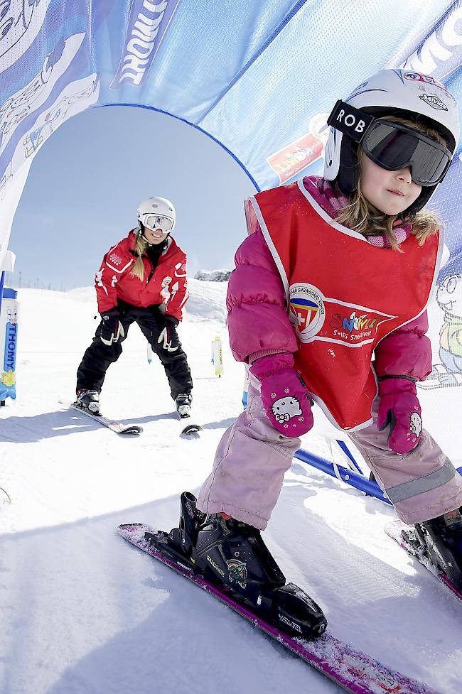 Ein Kind macht mit einer Skilehrerin erste Erfahrungen auf Skiern.