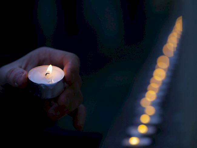 Ein Mann legt eine Kerze nieder. Beim tragischen Busunglück in Norditalien kamen mindestens 16 Menschen ums Leben. (Symbolbild)