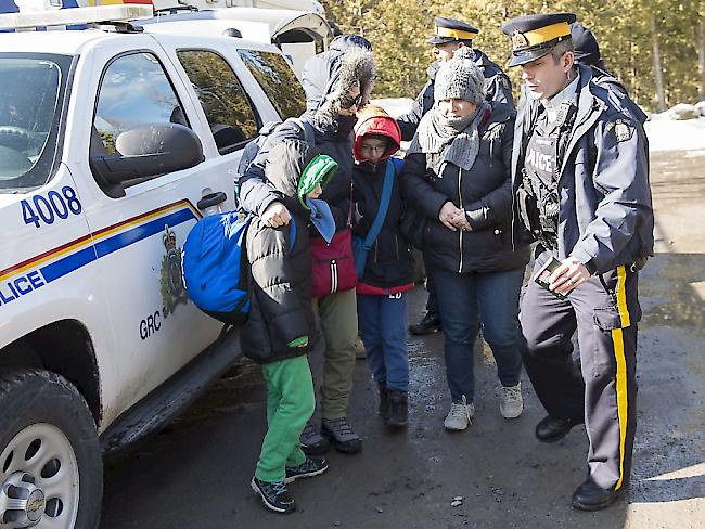Kanadische Polizisten nehmen eine Familie von Asylsuchenden an der Grenze zu den USA in Hemmingford in Empfang.