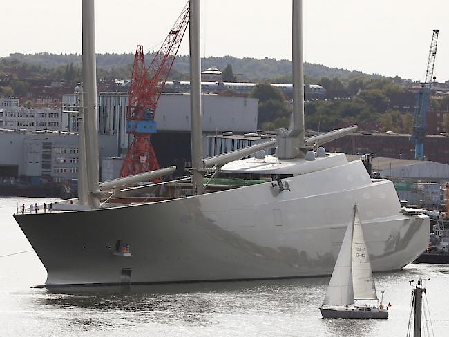 Die Segeljacht "Sailing Yacht A", wie sie am 16. September 2016 in Kiel für ein kurzes Wendemanöver aus dem Dock der Werft von Nobiskrug geschleppt wird, während ein Segelboot vorbeifährt.
