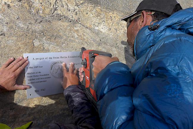 Ein pakistanischer Hochträger bringt am Gondogoro-Pass die Plakette der Swiss-Sherpa-Stiftung an.