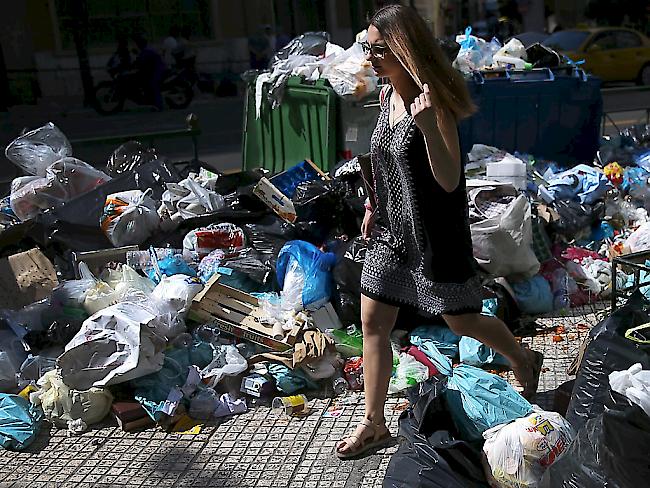Eine Frau sucht sich in Athen den Weg durch die Abfallberge - nach fünf Tagen Streik der Müllabfuhr türmen sich die Abfälle an fast jeder Ecke der griechischen Hauptstadt.