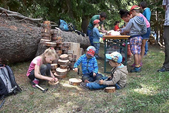 Die Kinder hämmern Nägel in ein Stück Holz um später mit Faden Muster zu machen.
