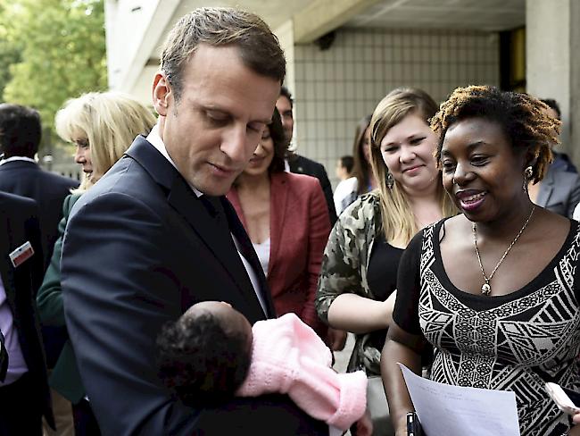 Frankreichs Präsident Emmanuel Macron hält ein Neugeborenes während eines Besuchs in einem Pariser Kinderspital (Archiv)