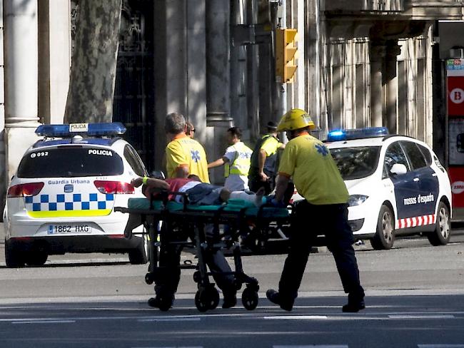 Helfer transportieren einen Verletzten in den Strassen Barcelonas