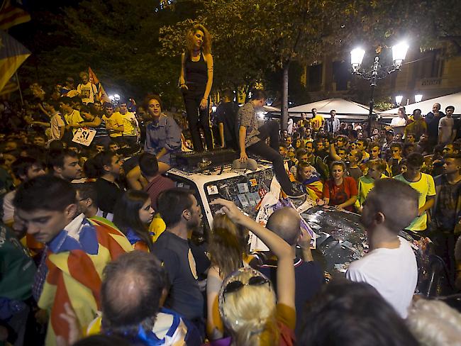 Demonstranten in Barcelona belagern ein Auto der spanischen Bundespolizei.