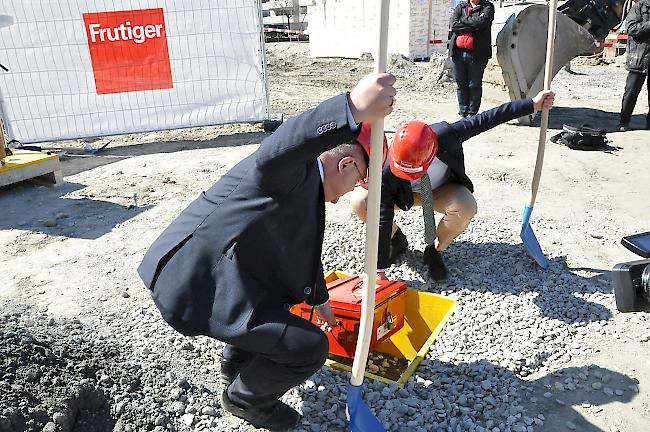 Gemeindepräsident Niklaus Furger und Thomas Frutiger, Chef der Frutiger AG, beim vergraben einer Kiste mit allerhand Lonza-Arena-Untensilien.