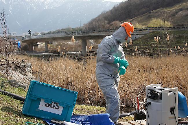 Mitarbeiter der Firma Bauer Umwelt in Schutzanzügen bei der Installation der Ansaugvorrichtung des vergifteten Wassers.