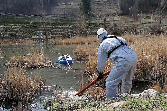 Mitarbeiter der Firma Bauer Umwelt in Schutzanzügen bei der Installation der Ansaugvorrichtung des vergifteten Wassers.