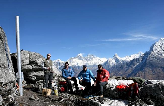 Patrick Kalbermatten, Bruno Jelk und die Sherpas Lakpa  und Thsering (von links) legen eine Arbeitspause ein mit Blick auf die höchsten Berge der Welt (von links Mount Everest, Lothse Shar, Ama Dablam, Makalu  und Tamserku). 