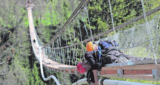 Luftig. Arbeiter montieren an der H&auml;ngebr&uuml;cke Kabelschutzrohre f&uuml;r den sp&auml;teren Einzug von Stromleitungen. 