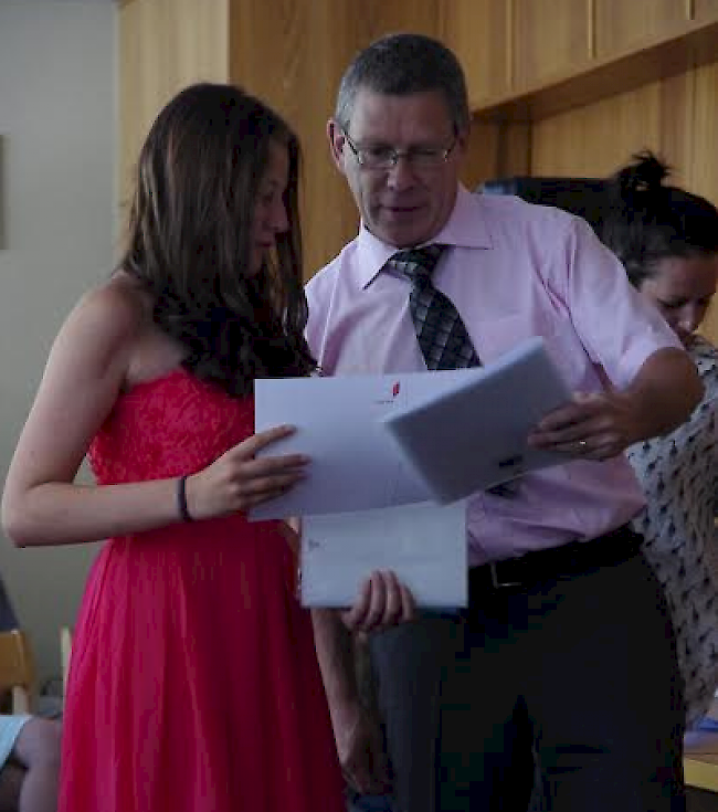 Schuldirektor Schwery überreicht einer Schülerin ihr OS-Diplom.