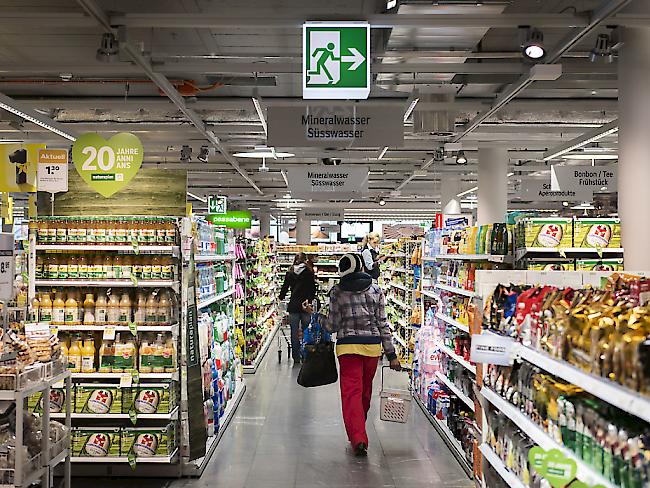 Eine Kundin geht in einem Coop-Supermarkt unter dem Wegweiser für den Notausgang durch (Archiv).