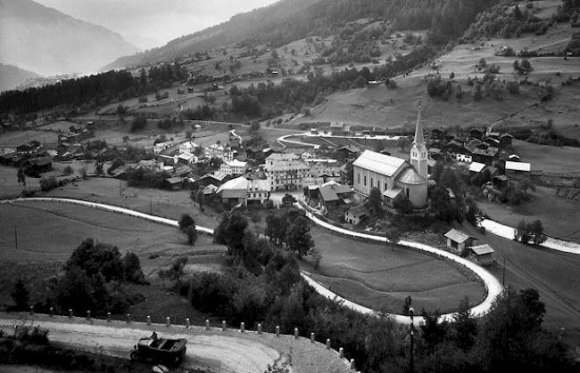 Gesamtübersicht über das Dorf Fiesch von Nordosten her. Das Gebiet der Klostermatte unterhalb des Bahnhofs und der Bahnlinie ist noch nicht überbaut. Im Grossen Kehr beherrscht ein einziges Auto die ganze Strasse für sich. Die ansteigenden Kehren der Furkastrasse sind sonst frei von Fahrzeugen. Die Aufnahme stammt wohl aus der Zeit vor 1930. 