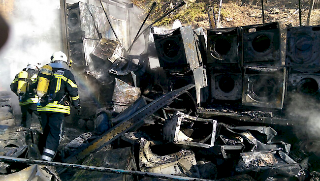 Feuerwehrleute räumen die zerstörte Fracht aus dem Anhängerzug.