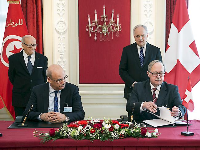 Alt Bundesrat Samuel Schmid (v.r.) und der tunesische Wirtscahfts- und Finanzminister Hakim Ben Hammouda (v.l.) unterschreiben das Dokument zur Gründung der Freundschaftsgruppe. Flankiert werden sie dabei von Bundespräsident Johann Schneider-Ammann (h.l.) und Tunesiens Präsident Béji Caïd Essebsi.