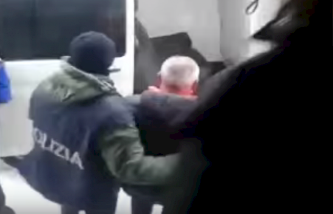 Verhaftung in Saas-Grund. Ein italienischer Beamter führt Antonio N. zu einem Kastenwagen.