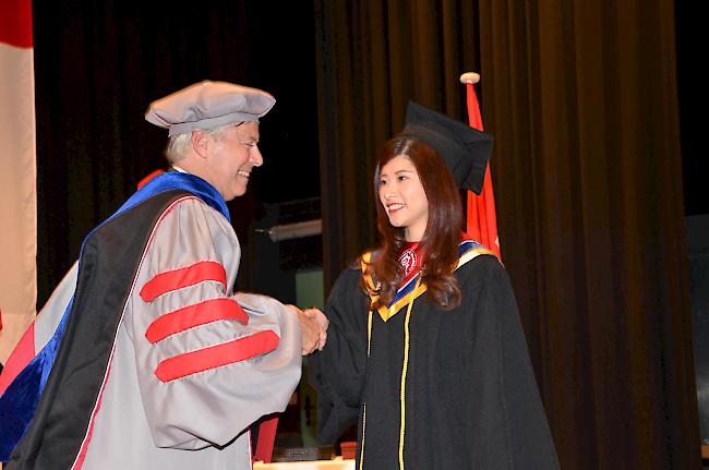 Larry Hunter von der Partneruniversität Washington State University übergibt ein Diplom an eine Absolventin.
