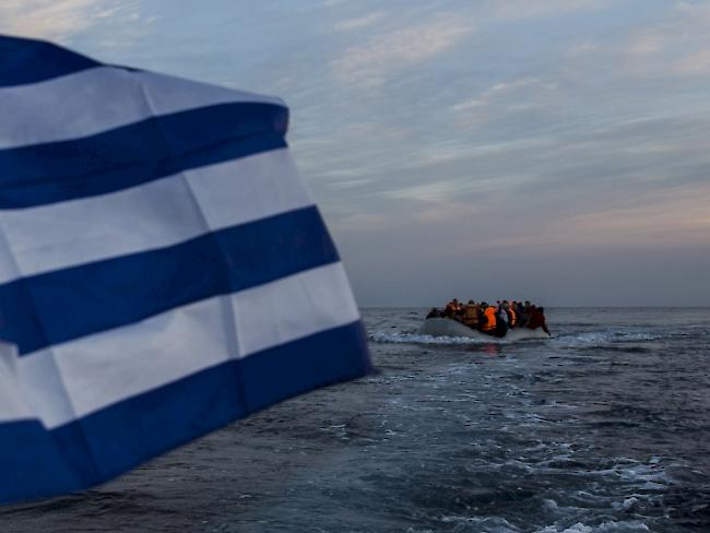 Flüchtlinge in einem Rettungsboot auf dem Weg an die griechische Küste. Im Vordergrund weht auf einem weiteren Boot eine griechische Flagge. (Archivbild)