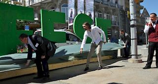 &Uuml;berraschung. Martin Schmidt (Mitte) enth&uuml;llt das riesengrosse Logo.