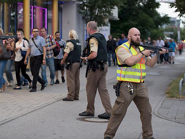Menschen verlassen das Olympia-Einkaufszentrum in München nach dem tödlichen Anschlag - die Polizei ist in Stellung.