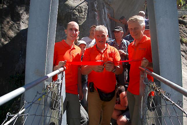 Reinhard Bittel, Präsident des Vereins Hängebrücke Aspi-Titter, schneidet an der Einweihung das Band durch. Dabei wird er vom Vize-Präsidenten Patrick Bizeau (links) und Kassier Peter Dittus flankiert. 