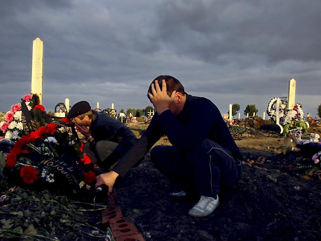 Ein Mann (l.) trauert auf einem Friedhof in Beslan gemeinsam mit seinem Bruder um seine Tochter, die beim Geiseldrama im Jahr 2004 starb. Bei der Erstürmung einer Schule waren über 330 Menschen getötet worden, darunter mehr als 180 Kinder. (Archiv)